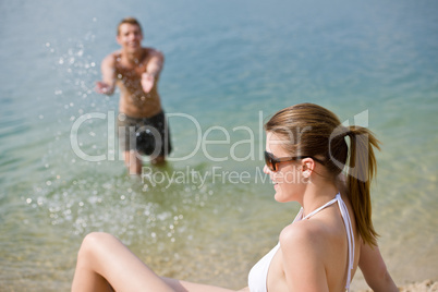 Couple on beach - woman in bikini sunbathing