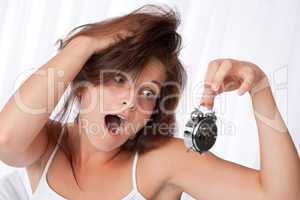 Surprised woman watching alarm clock