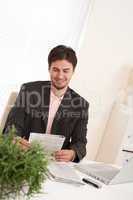 Successful modern businessman with laptop and newspaper