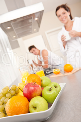 Bowl with fruits, couple in the background
