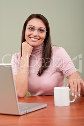 Smiling secretary with coffee and laptop at office