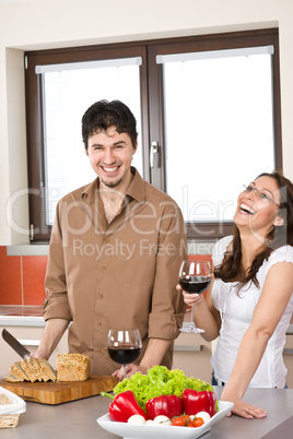 Happy couple in modern kitchen drink red wine