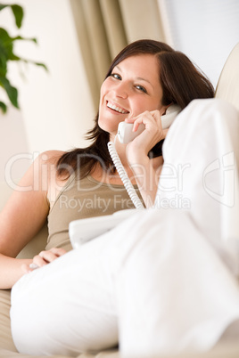 On the phone home: Young woman calling in lounge