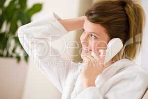 Happy woman in white bathrobe with phone home