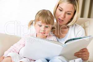 Mother with surprised little girl read book together
