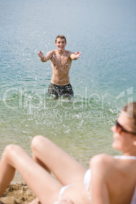 Couple on beach - woman in bikini sunbathing