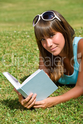 Smiling young woman lying down on grass with book Smiling young woman lying down on grass with book