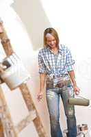 Home improvement: Young woman with paint roller and ladder