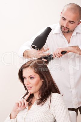 Professional hairdresser with hair dryer at salon with customer