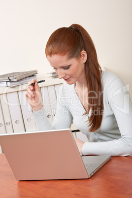 Long red hair woman working at office with laptop