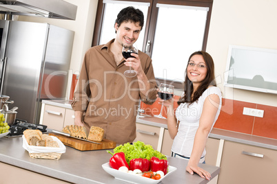 Happy couple in modern kitchen drink red wine