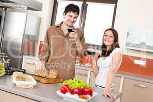 Happy couple in modern kitchen drink red wine