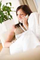 On the phone home: Young woman calling in lounge