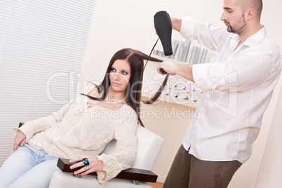 Professional hairdresser with hair dryer at salon