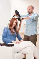 Professional hairdresser with hair dryer at salon