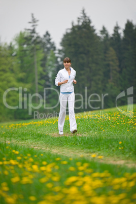 Jogging - sportive woman running in park with dandelion