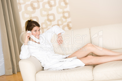 Happy woman in white bathrobe with phone