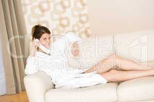 Happy woman in white bathrobe with phone