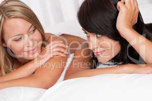 Blond woman and brunette having fun in bed