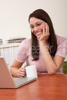 Smiling secretary with coffee and laptop at office