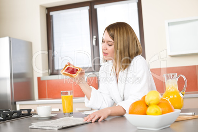 Breakfast - Smiling woman reading newspaper in kitchen