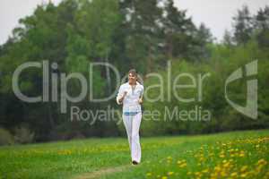 Jogging - sportive woman running in park with dandelion