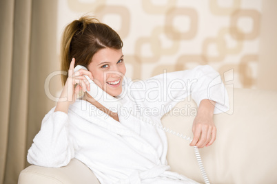 Happy woman in white bathrobe with phone