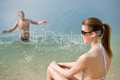 Couple on beach - woman in bikini sunbathing