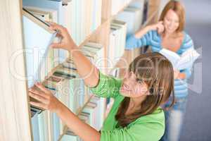 Student in library - two happy woman choose book
