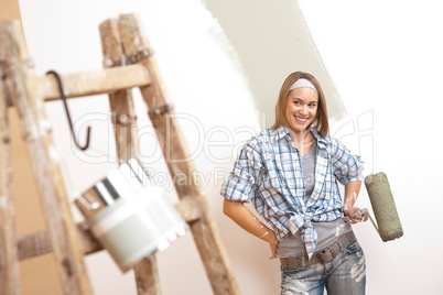 Home improvement: Young woman with paint roller and ladder