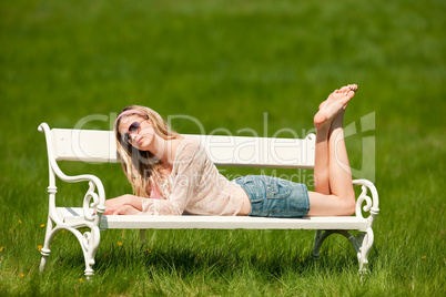 Spring - Young woman relaxing on bench in meadow