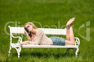 Spring - Young woman relaxing on bench in meadow