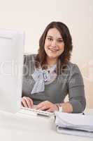 Happy businesswoman sitting at office desk