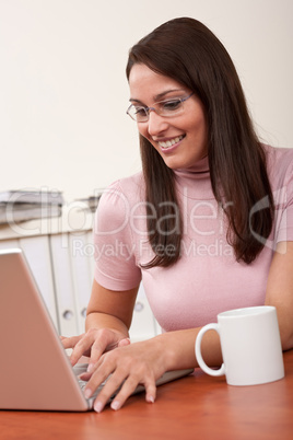 Smiling secretary with coffee and laptop at office