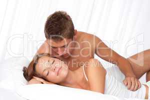 Young man and woman lying down in white bed