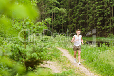 Sportive man jogging in nature by lake