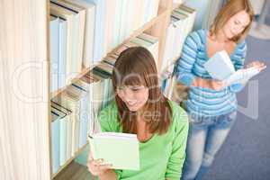 Student in library - two happy woman read book