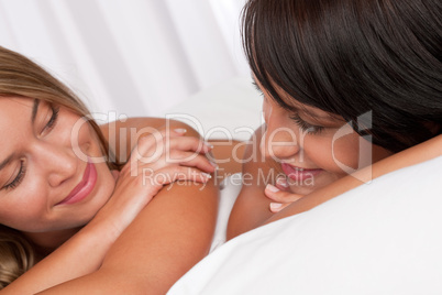 Blond woman and brunette having fun in bed