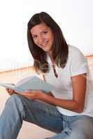 Happy teenager sitting with book