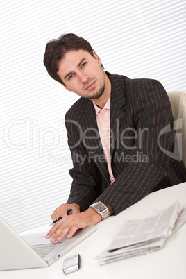 Successful modern businessman with laptop and newspaper