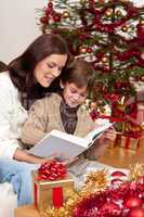 Young mother with son reading book on Christmas