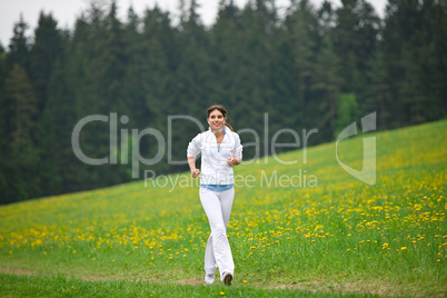 Jogging - sportive woman running in park with dandelion