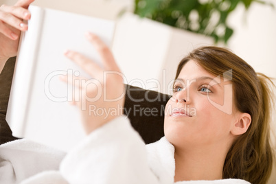 Young woman read book lying down on sofa