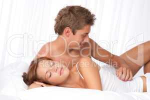 Young man and woman lying down in white bed