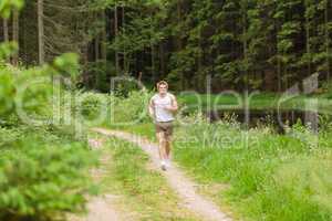 Sportive man jogging in nature by lake