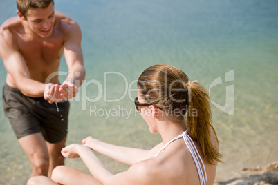 Couple on beach - woman in bikini sunbathing