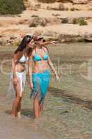 Two attractive woman walking on the beach