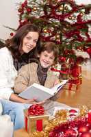 Young mother with son reading book on Christmas