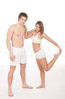 Fitness - Young couple stretching after training on white