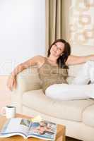 Young woman with magazine and coffee on sofa